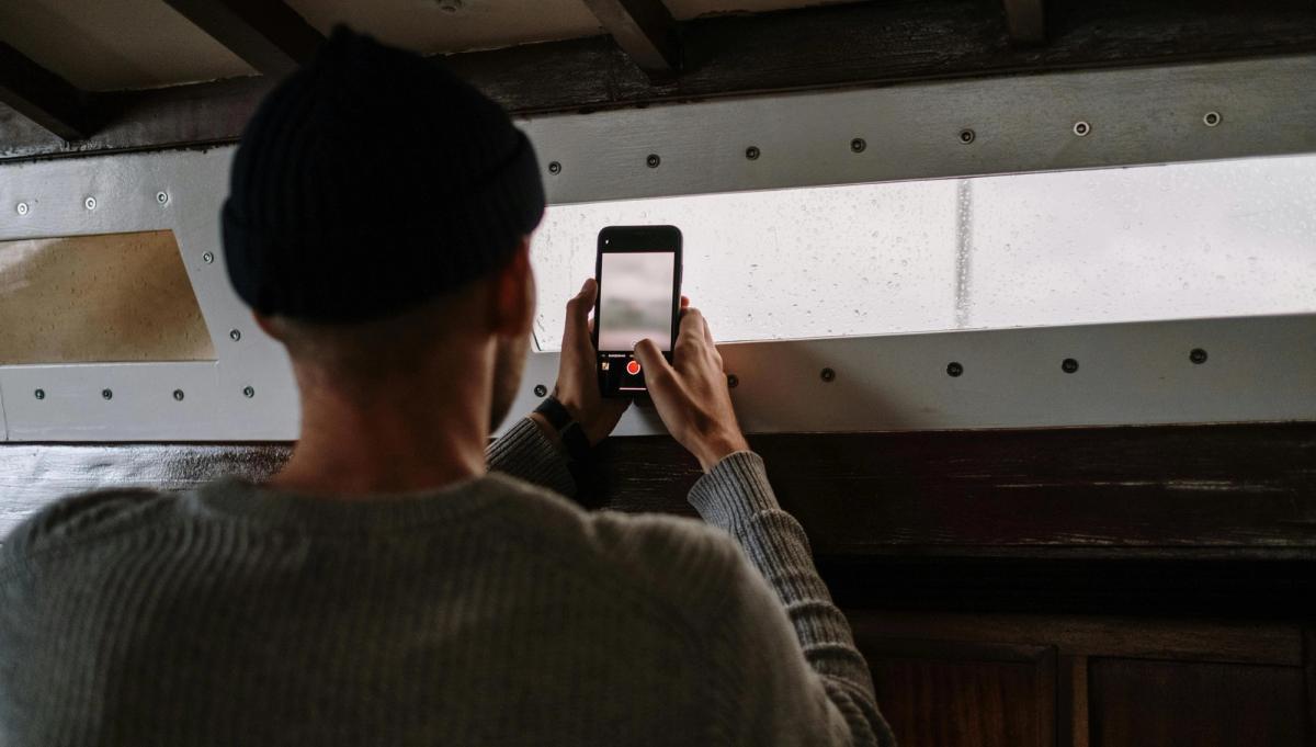 Locataire photographiant des moisissures sur un mur avec son smartphone pour constituer un dossier de preuves