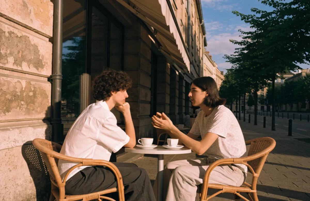Deux personnes discutent autour d'un café lors d'une rencontre entre futurs colocataires