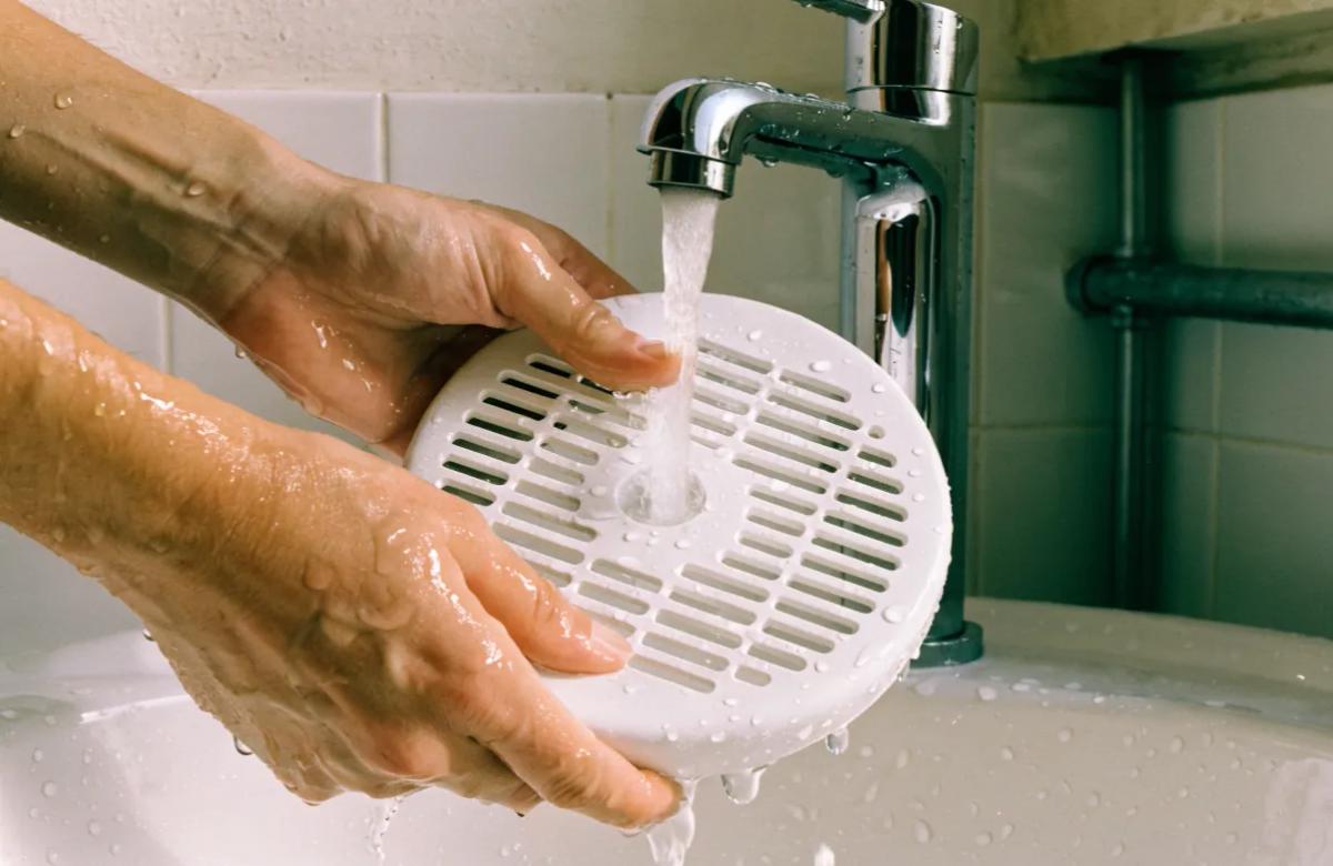 Locataire nettoyant une bouche d'extraction de VMC dans une salle de bains