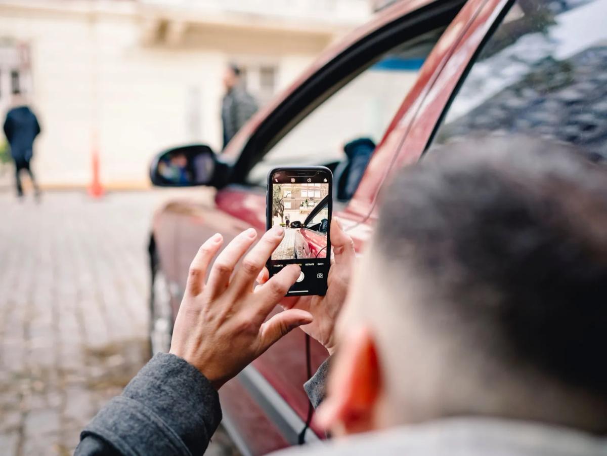 Personne photographiant un véhicule mal stationné avec son smartphone pour constituer un dossier de preuves