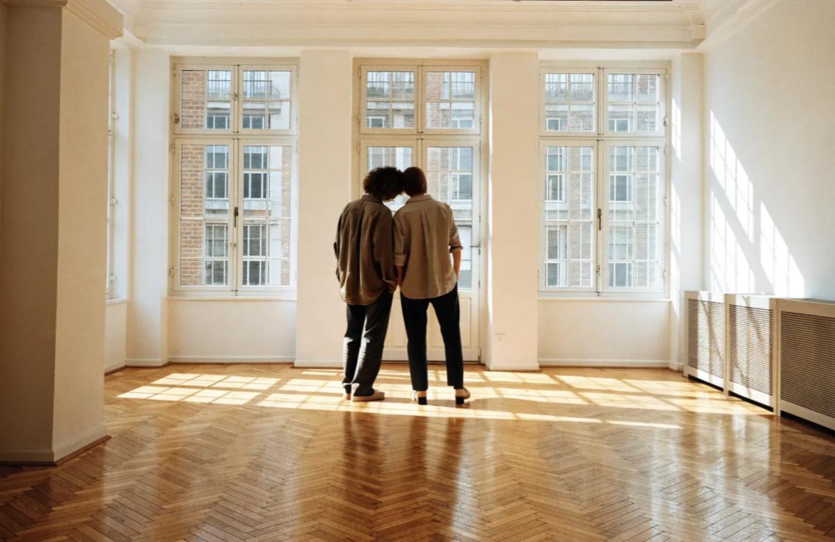 Jeune couple visitant un appartement lumineux avec un agent immobilier