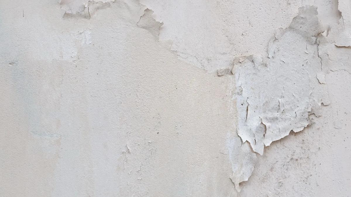 Peinture cloquée et traces d'humidité sur le mur d'un logement après un dégât des eaux