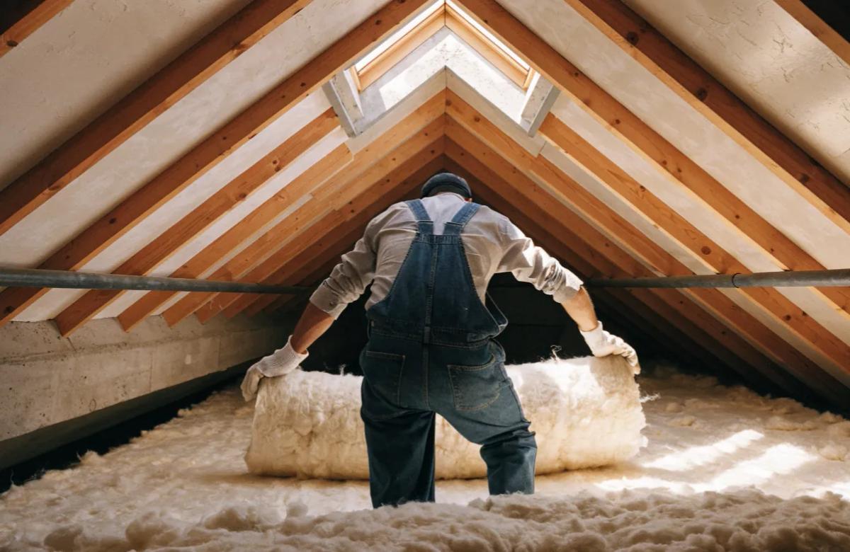 Ouvrier réalisant l'isolation des combles d'un logement en rénovation énergétique