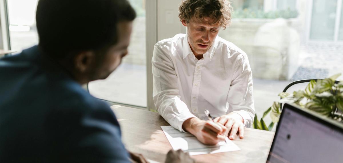 Locataire et propriétaire en train de discuter d'un contrat de bail autour d'une table