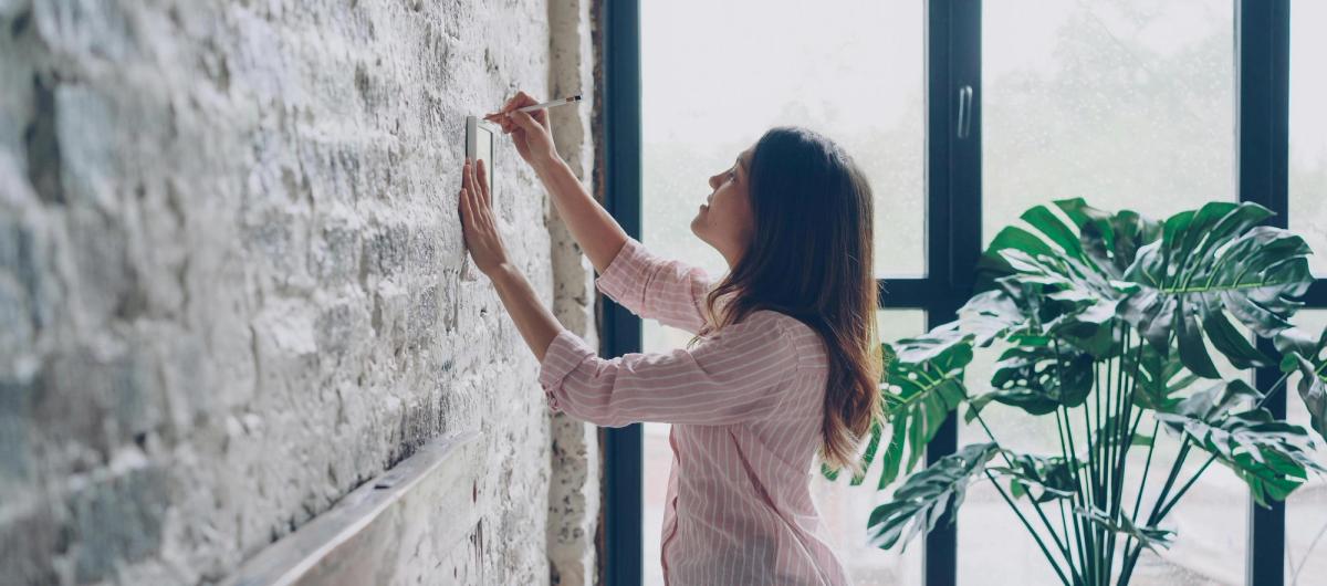 Locataire accrochant un tableau au mur de son appartement