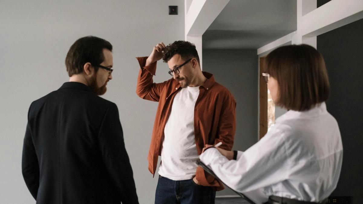 Locataire discutant avec un propriétaire devant la porte d'un appartement lors d'un litige sur des travaux