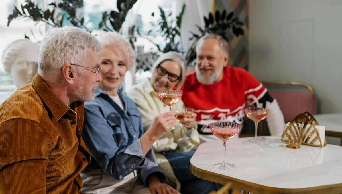 Espace commun lumineux d'une résidence services seniors avec des retraités discutant autour d'une table