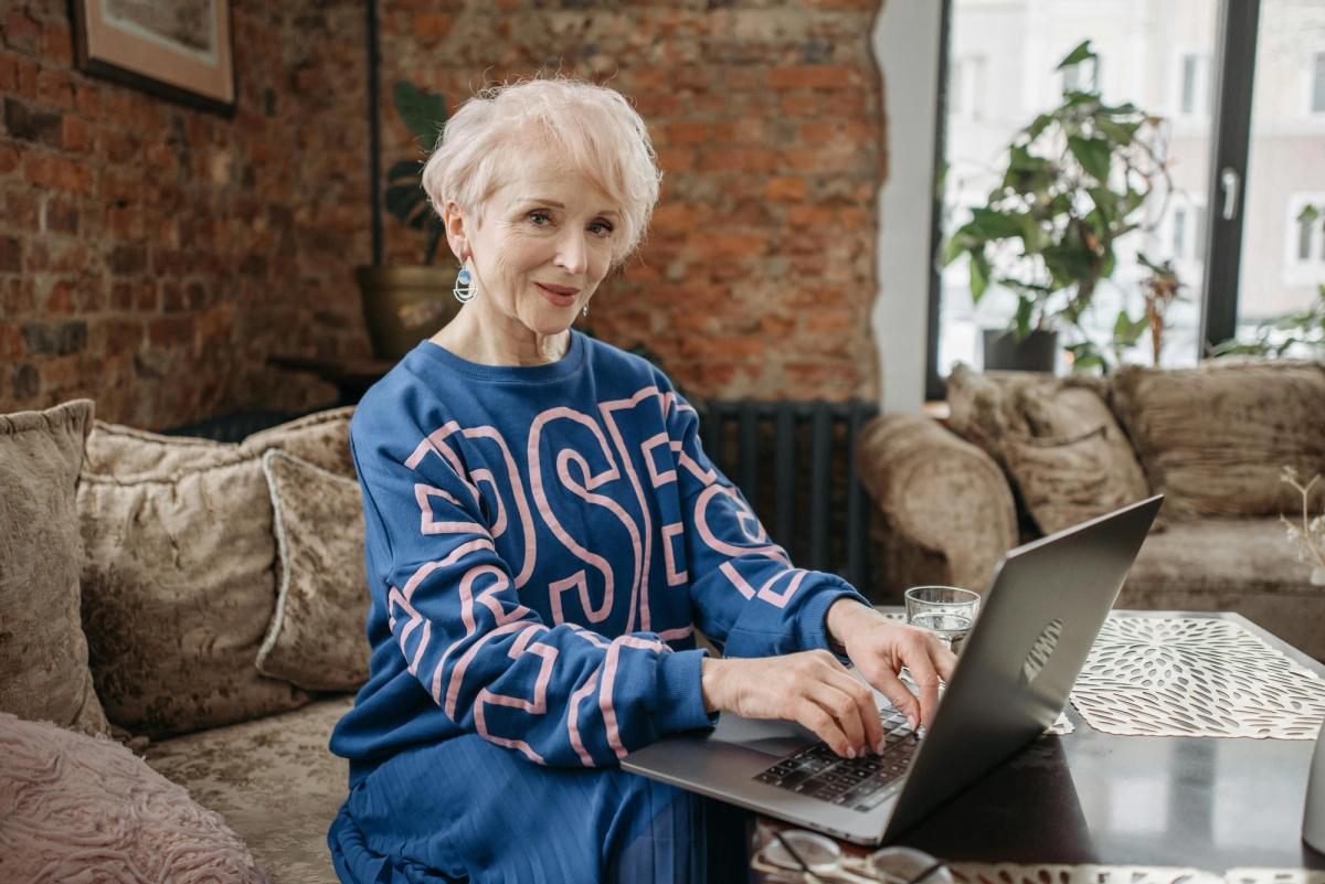 Senior souriant devant un ordinateur, en train de rechercher un logement en ligne