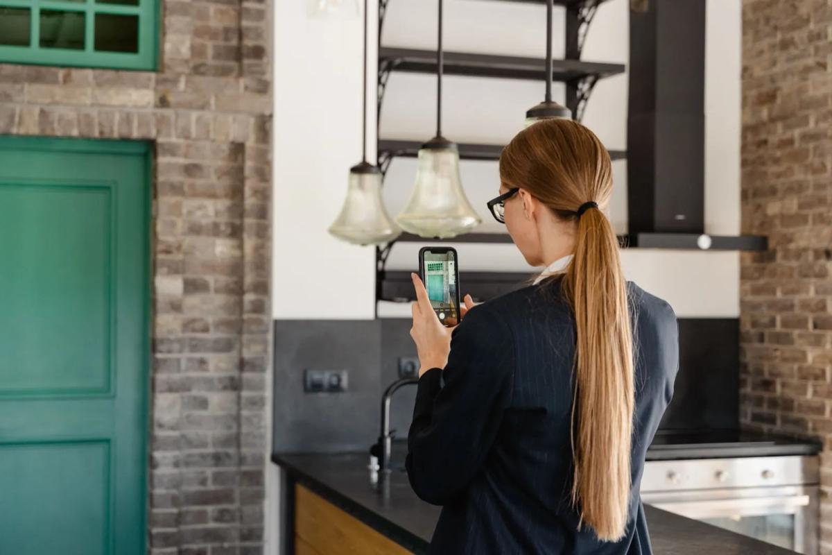 Jeune locataire réalisant l'état des lieux d'entrée d'un appartement avec son smartphone