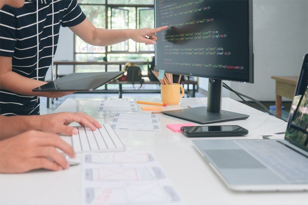 Website developers working at dual desktop monitors