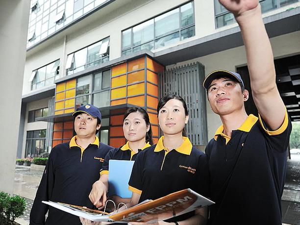 Four people in matching uniforms stand outside a modern building.
