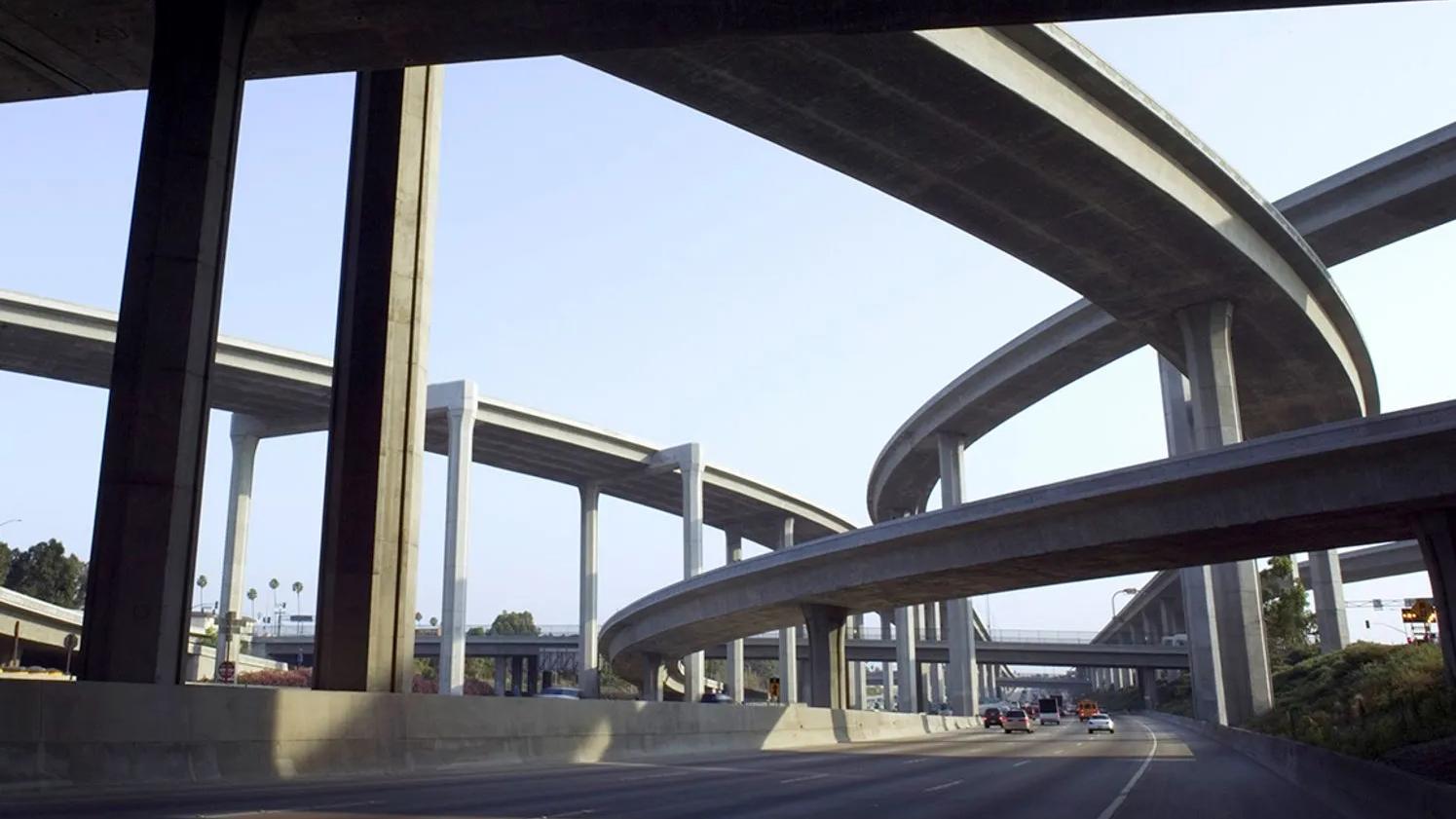 A complex network of elevated highway overpasses and ramps, with multiple levels of concrete structures intersecting against a clear sky.