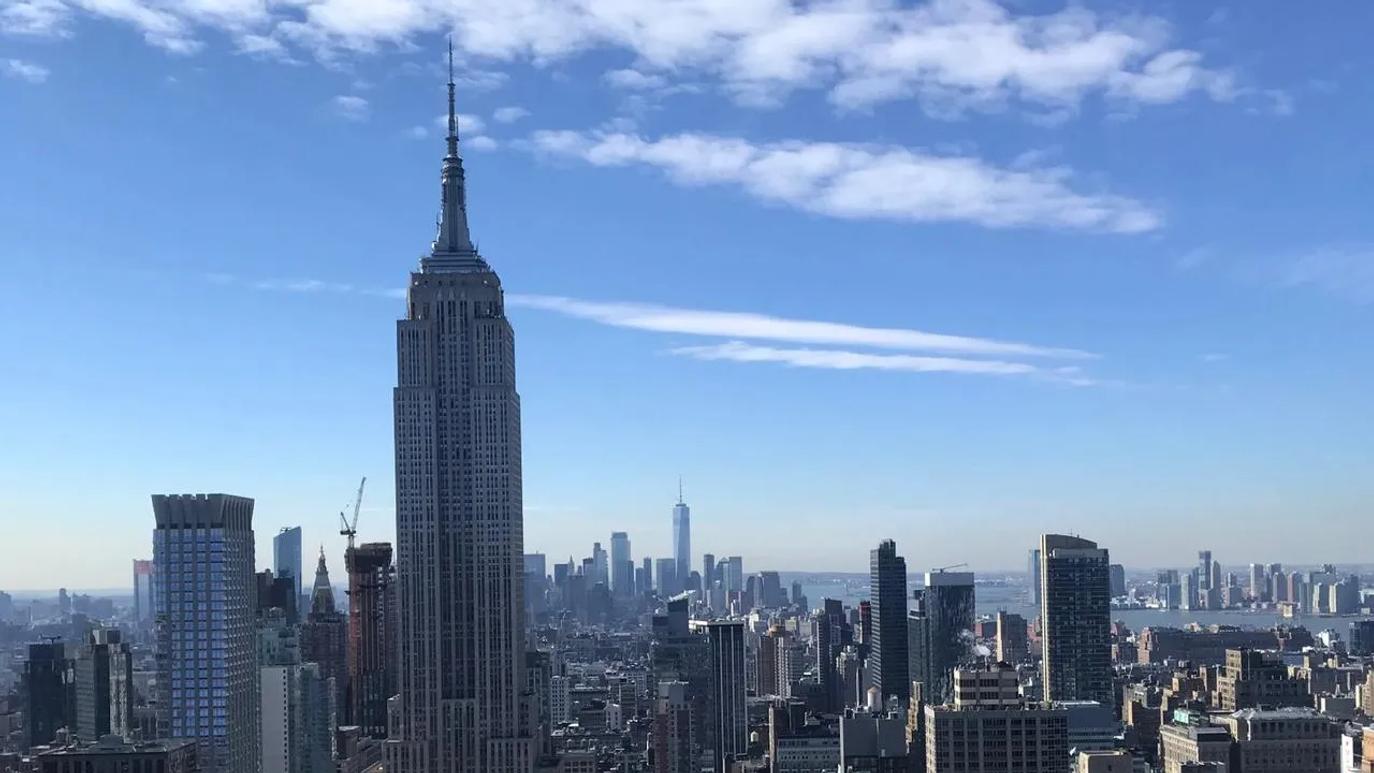 Skyline of New York City featuring the Empire State Building under a clear blue sky.