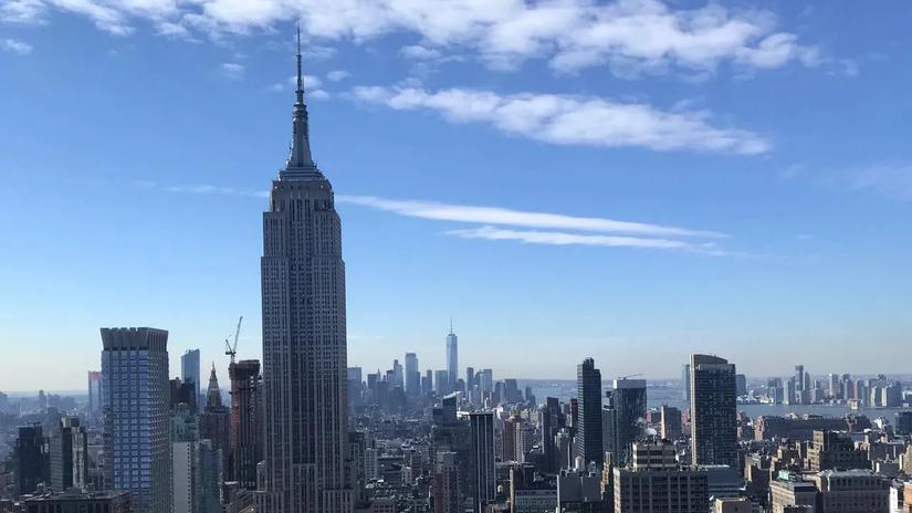 Skyline of New York City featuring the Empire State Building under a clear blue sky.