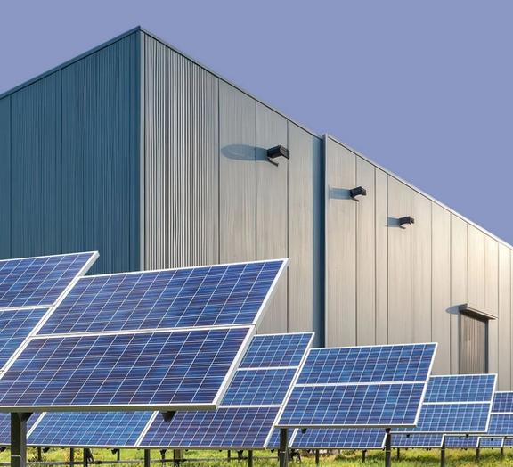 Solar panels arrayed in front of a warehouse.