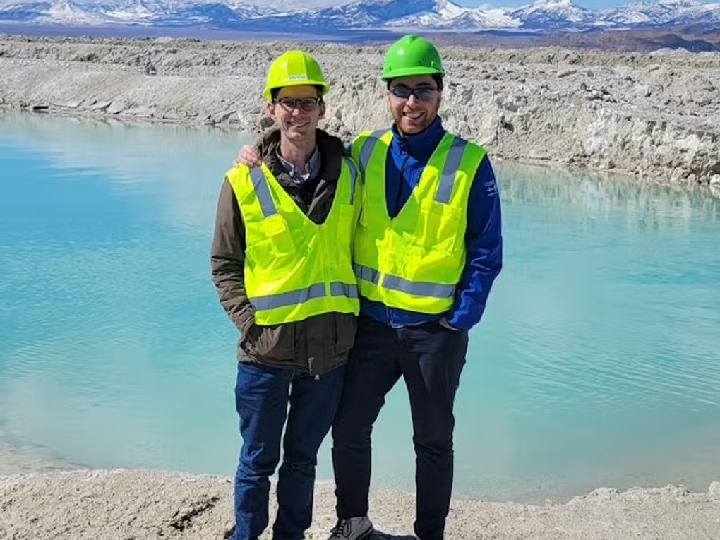 Two people standing by a lake.