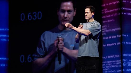 A man gestures to the crowd from a stage.