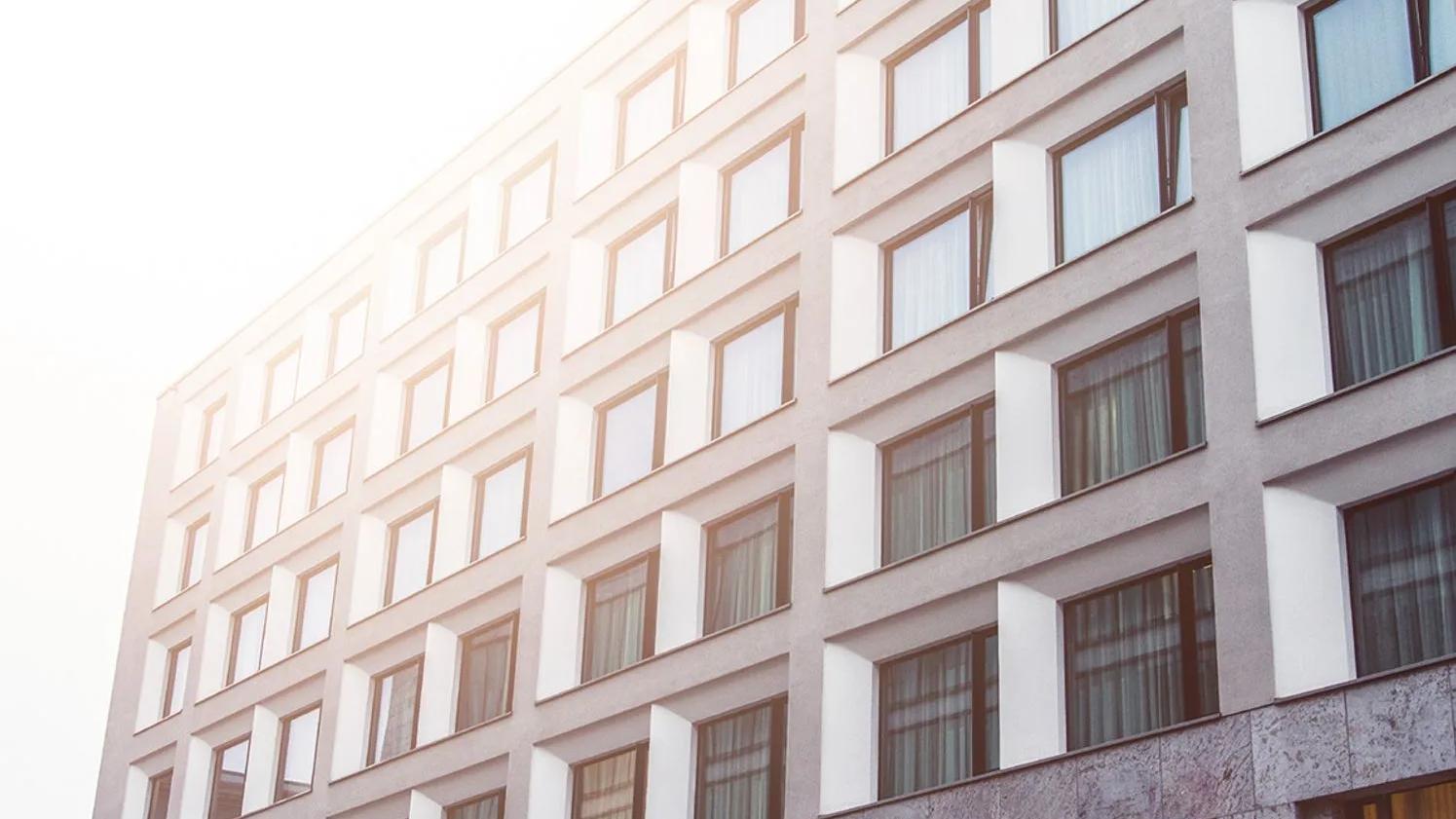 A modern building facade with a grid of windows, reflecting sunlight, creating a warm and bright atmosphere.