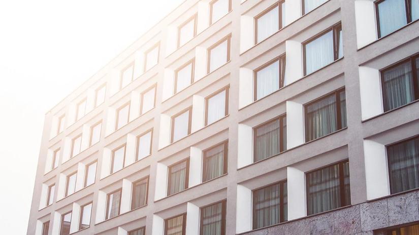 A modern building facade with a grid of windows, reflecting sunlight, creating a warm and bright atmosphere.