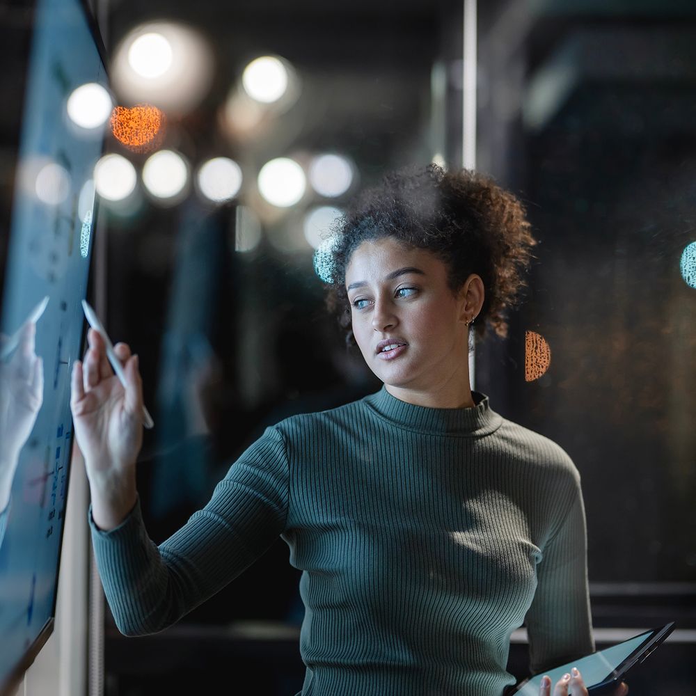 A woman points at a screen. 