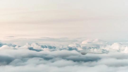 A serene view of fluffy clouds from above, with a soft, pastel sky in the background.
