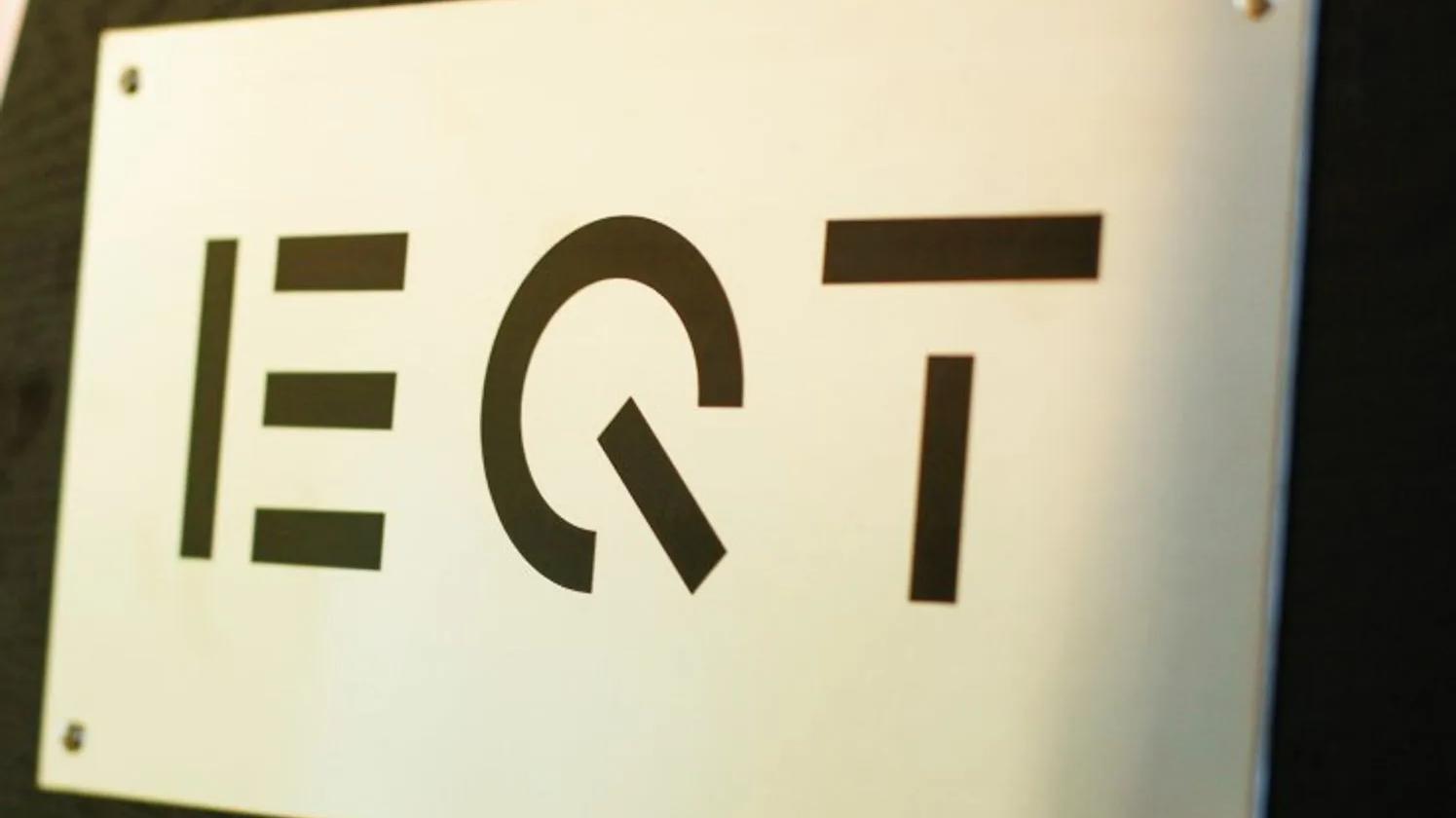 A metal plaque with the EQT logo in bold black letters mounted on a wall.