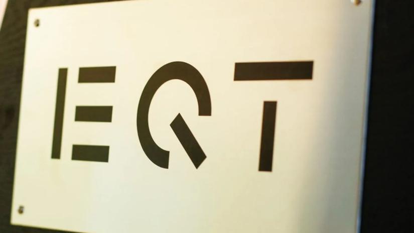 A metal plaque with the EQT logo in bold black letters mounted on a wall.