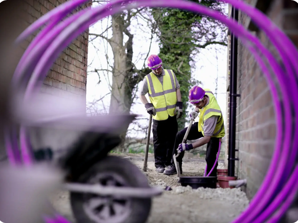 Two workers setting up fiber cables to a home