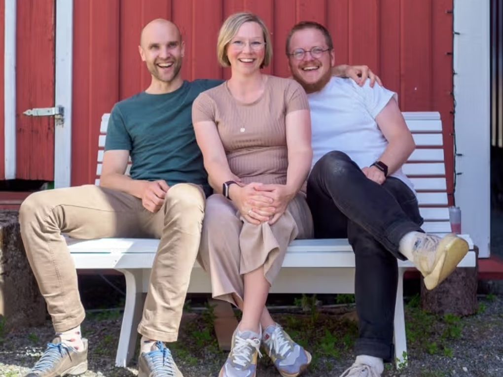 Three people sitting on a bench.