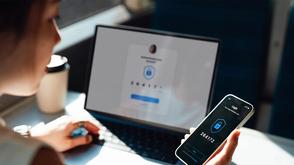 Woman looking at her mobile phone while on her laptop