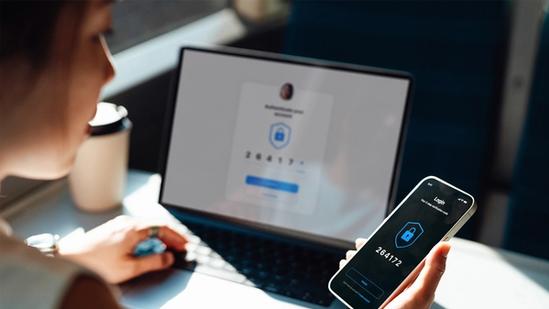 Woman looking at her mobile phone while on her laptop