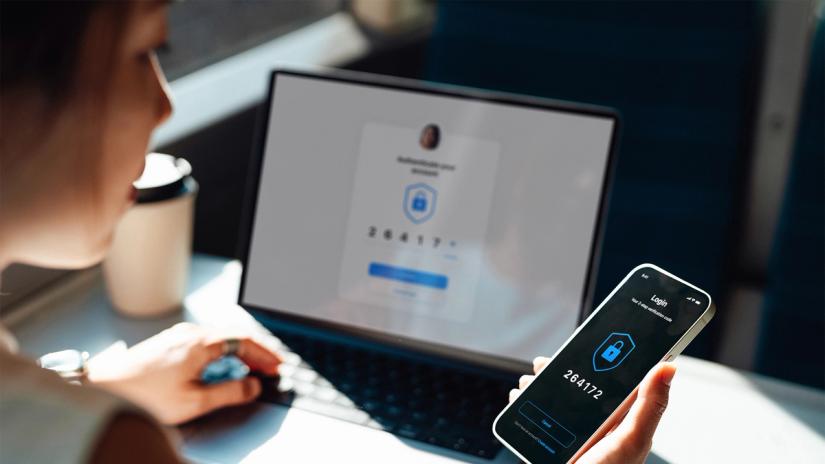 Woman looking at her mobile phone while working on her laptop