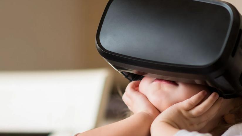 A child wearing a virtual reality headset, resting their chin on their hands.