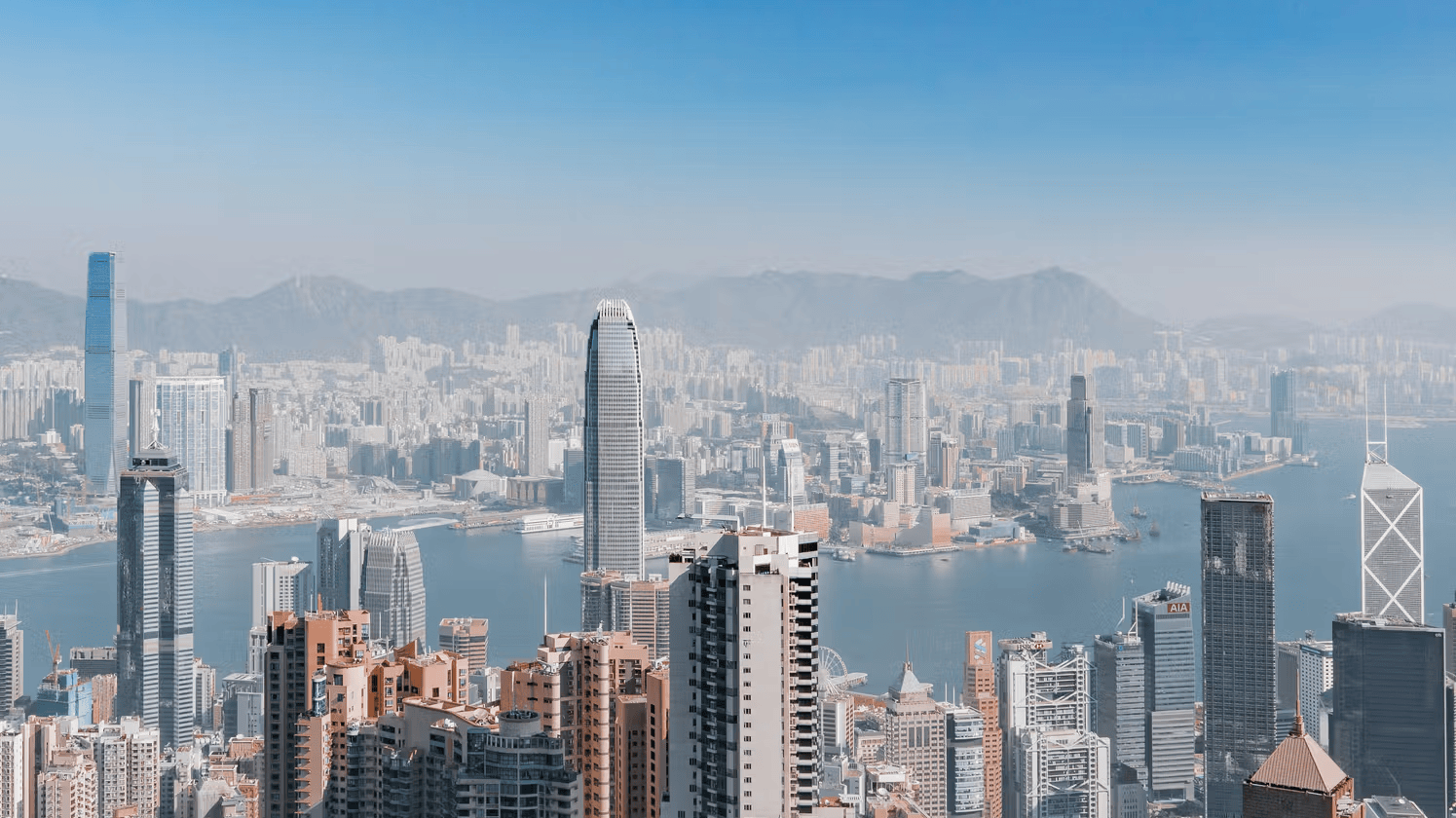Aerial view of Hong Kong's skyline with tall skyscrapers and Victoria Harbour in the background under a clear blue sky. Copy message Loading... Scroll to bottom ? Help