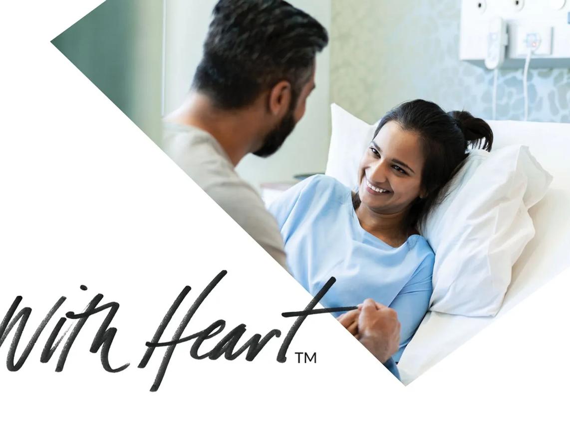 A woman in a hospital bed smiling at a man holding her hand.