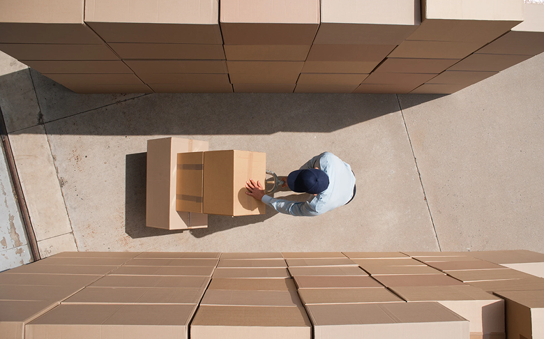 A worker carrying cardboard boxes with a trolley 