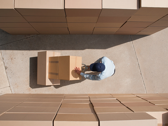 A worker carrying cardboard boxes with a trolley