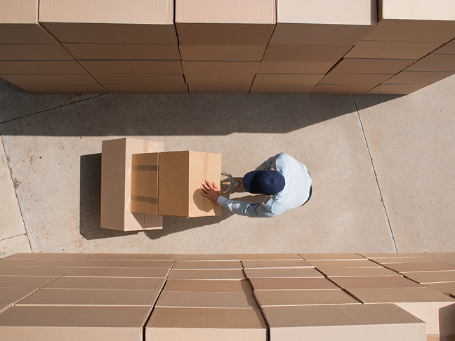 A worker carrying cardboard boxes with a trolley