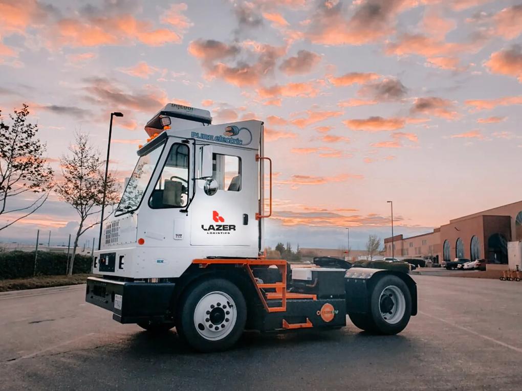 A white truck labeled "Lazer Logistics" parked on a road at sunset.