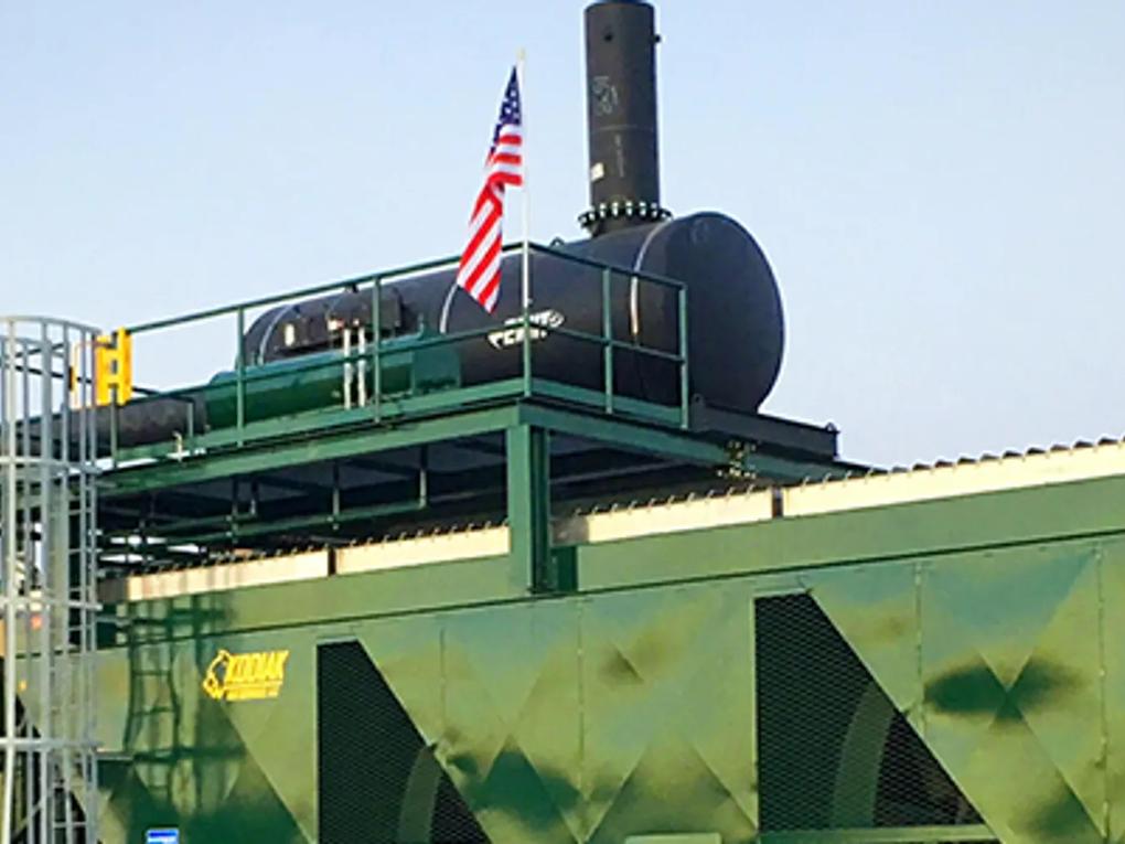 A large industrial unit with a green exterior and an American flag on top.