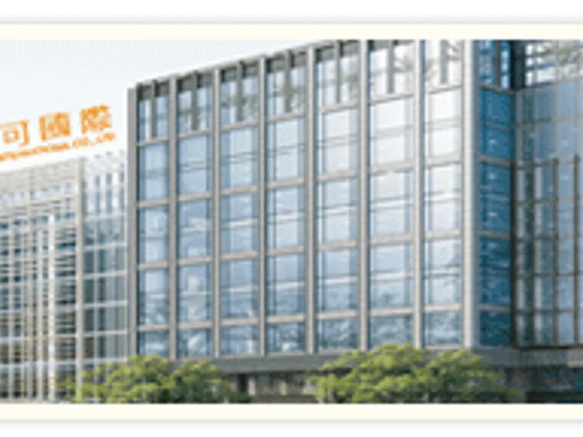 A modern glass office building with reflective windows, surrounded by greenery.