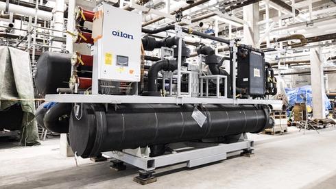 Industrial refrigeration or heat pump system with large black insulated pipes and an Oilon control unit installed in a mechanical plant room.