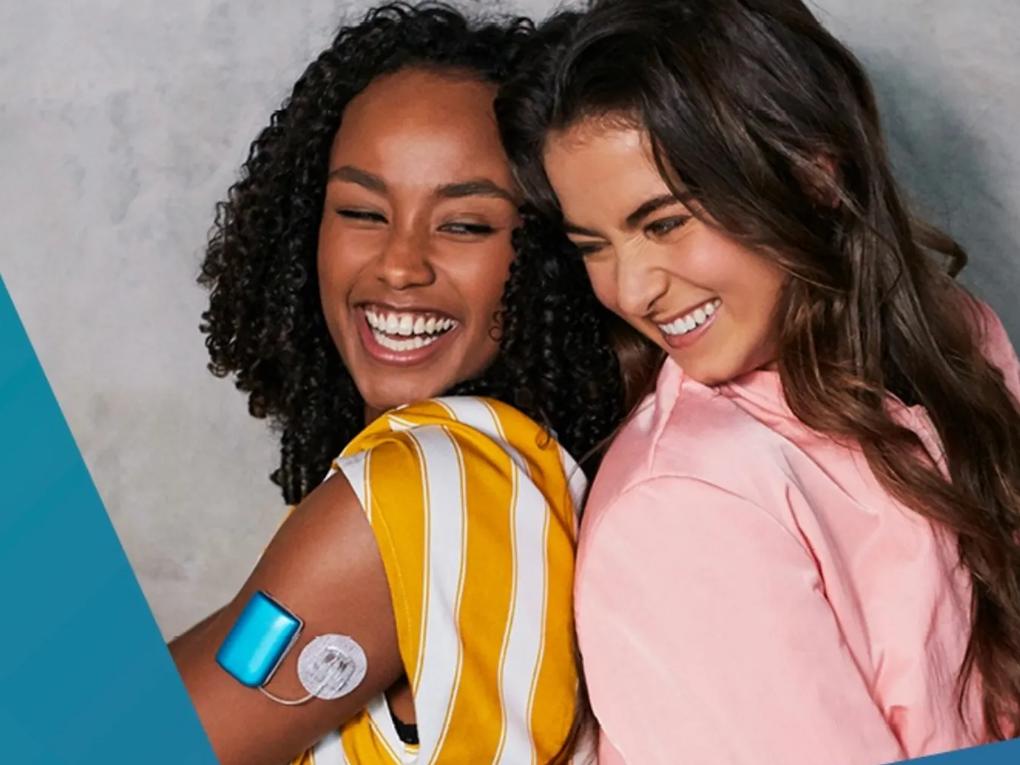 Two smiling women leaning back-to-back.