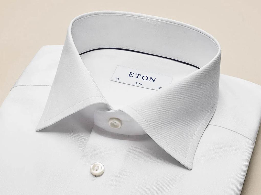 A neatly folded white dress shirt with a label reading "ETON" inside the collar.