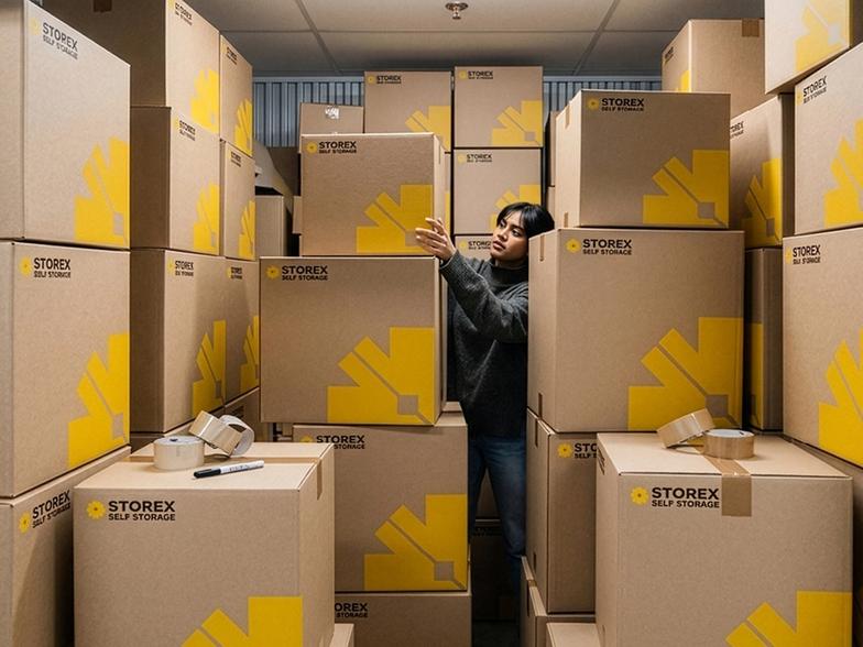 A person standing in a storage with a lot of Storex boxes.