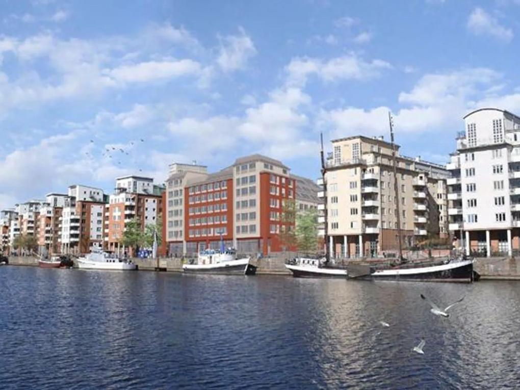 A waterfront view of modern apartment buildings with boats docked along the quay.