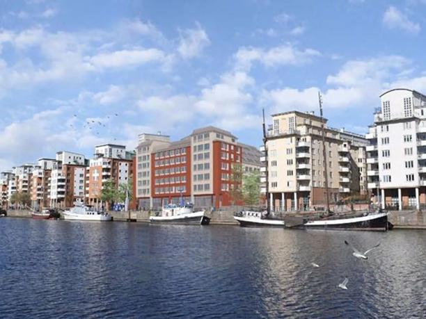 A waterfront view of modern apartment buildings with boats docked along the quay.