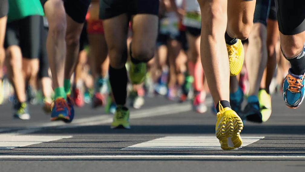 Runners in a marathon, focusing on their legs and colorful running shoes on the road.