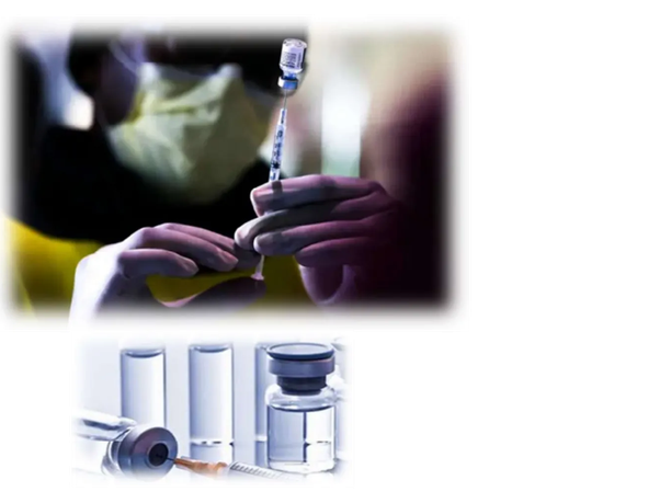 A person wearing a mask prepares a syringe with a vaccine vial.