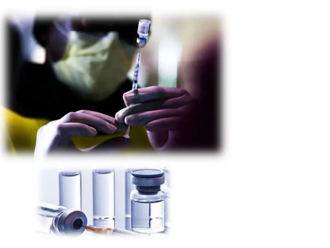 A person wearing a mask prepares a syringe with a vaccine vial.